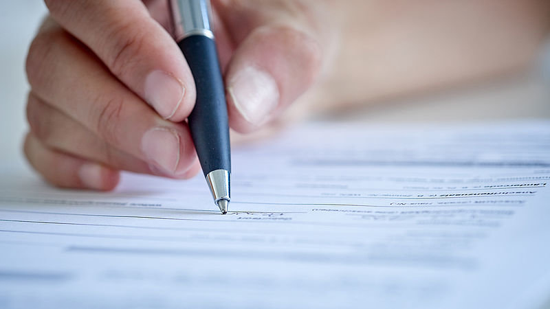 Schreibende Hand auf einem Antragsformular