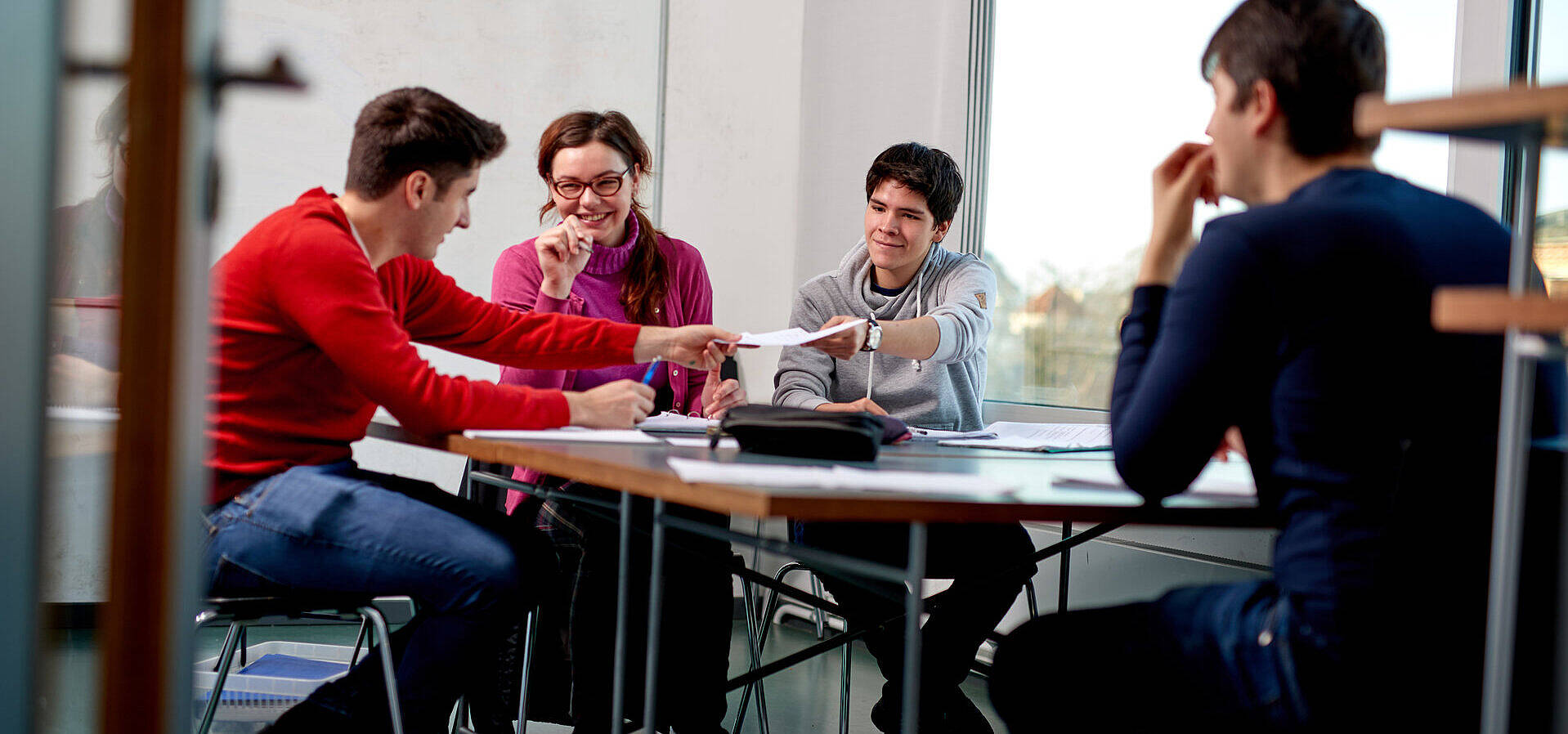 Studierende der Technischen Universität Berlin in einem Arbeitsraum arbeitend, als Gruppe an einem Tisch sitzend und sich austauschend