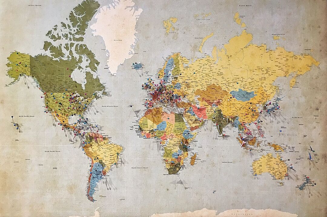 Weltkarte mit vielen durch bunte Pins markierten Orte auf allen Kontinenten
