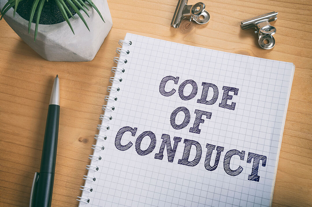a writing pad on a desk, the pad says "code of conduct"