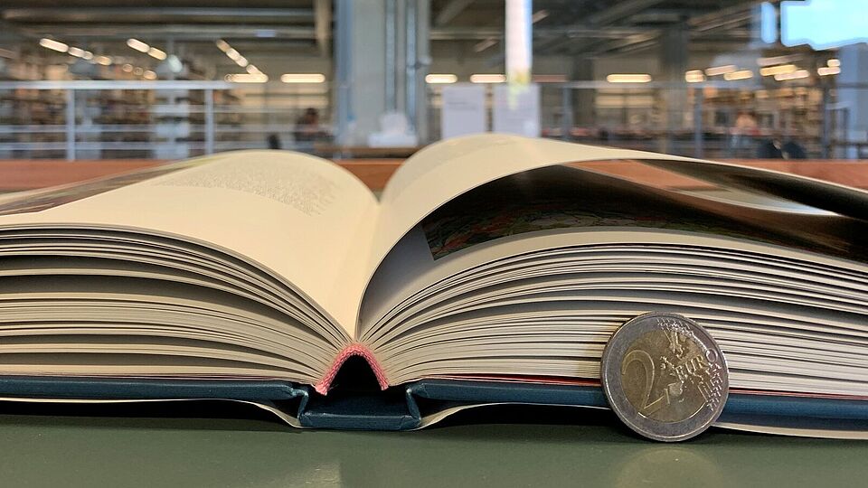aufgeklapptes Buch mit Zwei-Euro-Münze