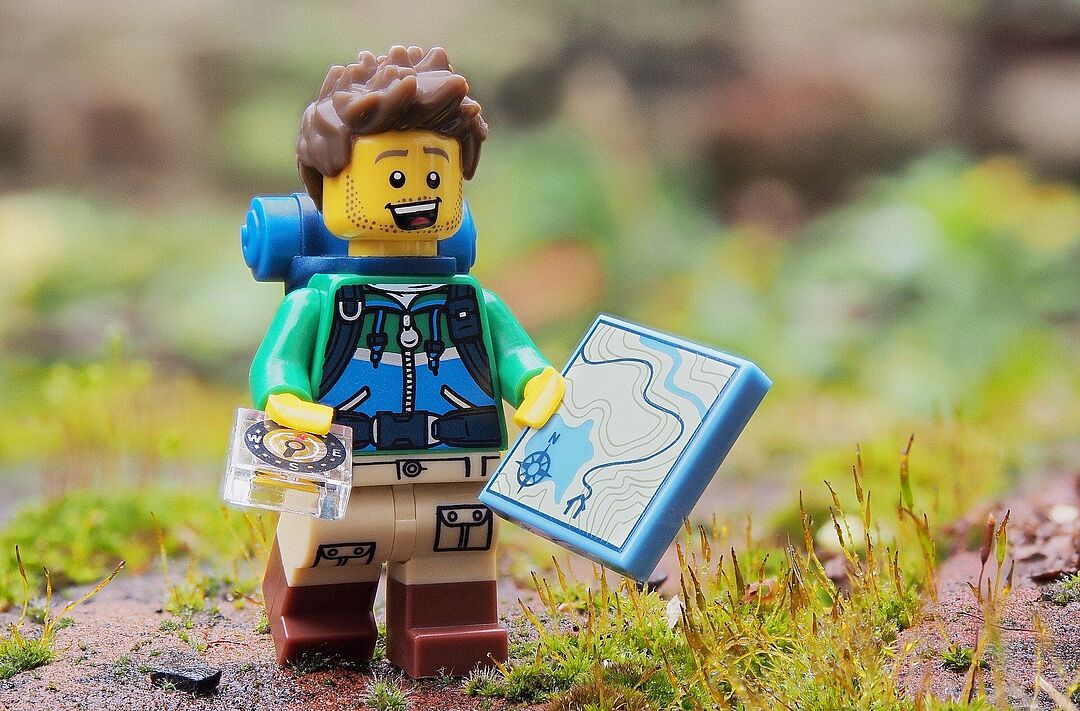 Lego-Figur mit Kompass und Landkarte