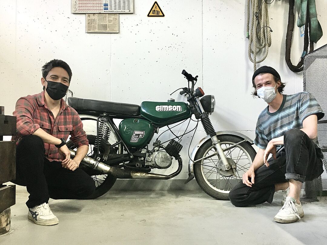 Zwei Personen neben einem Moped