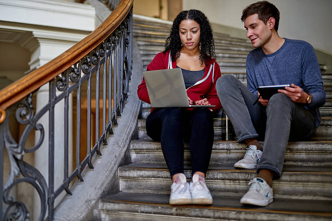 Zwei Studierende sitzend auf einer Treppe