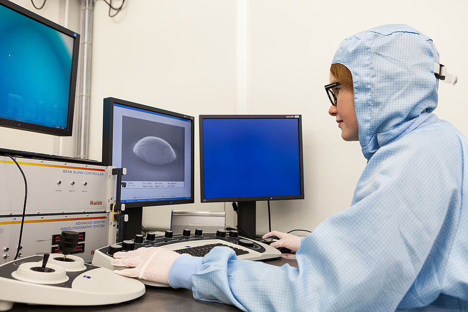 Eine wissenschaftliche Mitarbeiterin arbeitet an einem Elektronenrastermikroskop