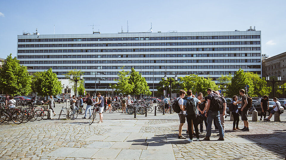 View of TU Berlins main building across Straße des 17. Juni in sunshine, students are standing in groups