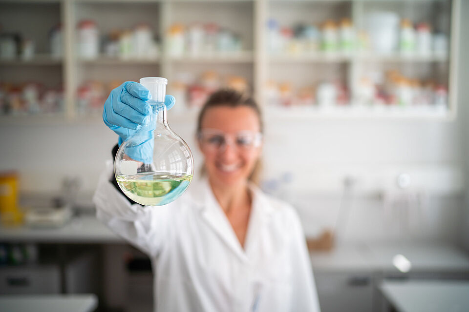 Wissenschaftliche Mitarbeiterin in einem Labor mit einem Erlenmeyerkolben