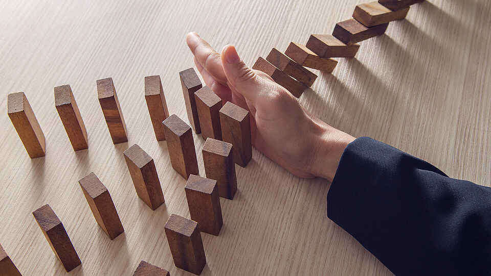 Geschäftsfrau Hand stoppen das Domino Holzeffekt-Konzept für die Geschäftswelt.