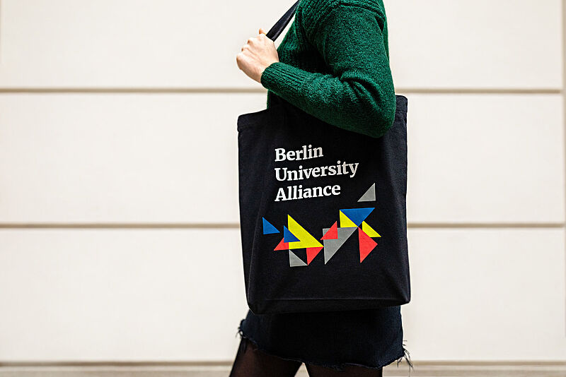 Person mit dem Beutel der Berlin University Alliance