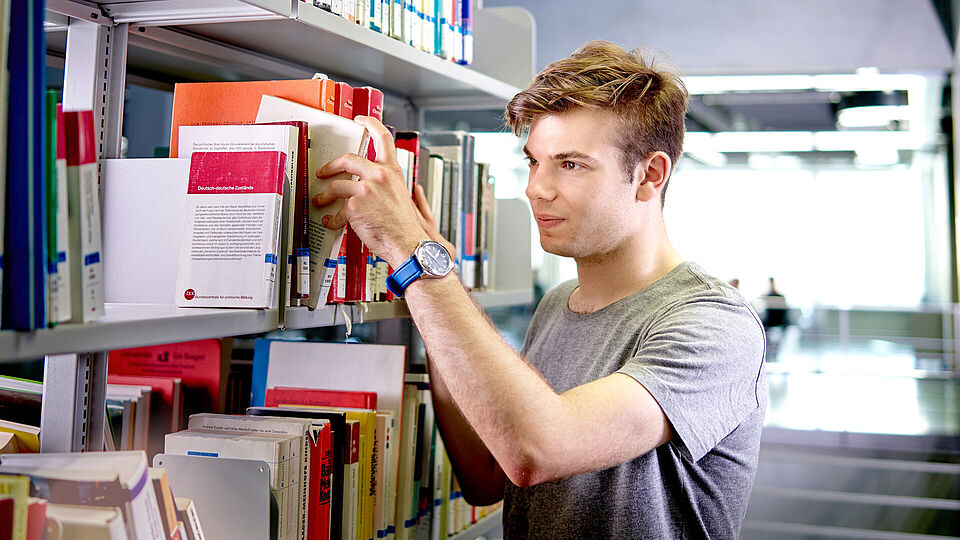 Student takes book from shelf