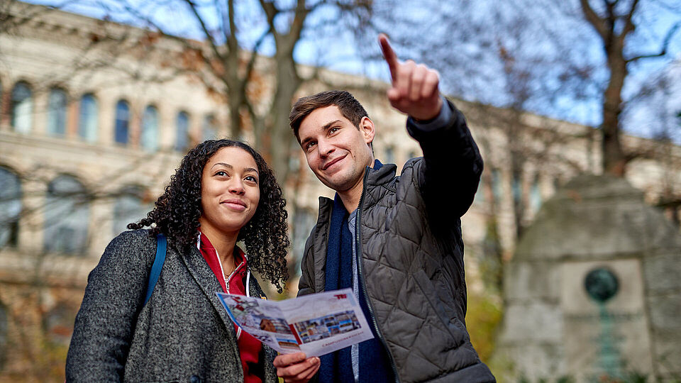 Studierende auf dem Campus der Technischen Universität Berlin mit einer Campuskarte in der Hand